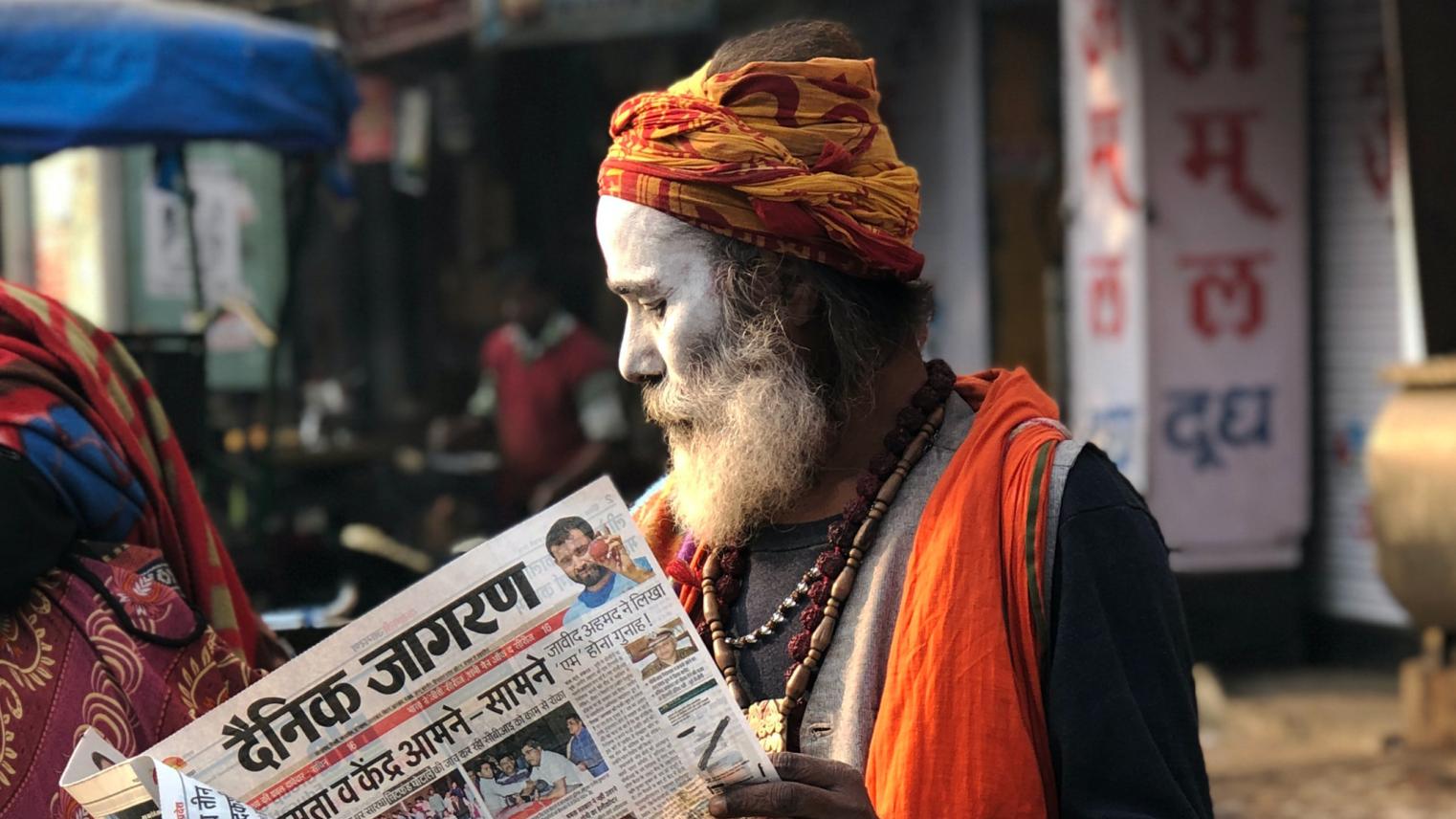 Man reading newspaper beside street 